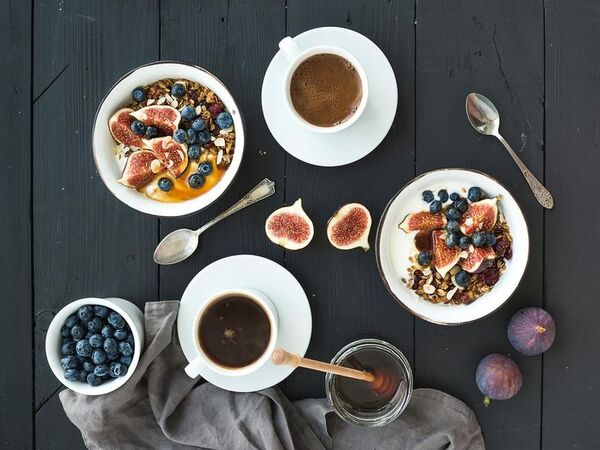 Table with a simple breakfast bowl, fruit, and coffee